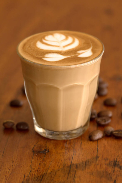 Koffie piccolo latte op houten bureau in koffieshop. - Foto, afbeelding