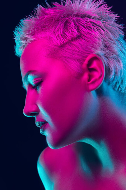 Portrait of female fashion model in neon light on dark studio background. - Photo, Image