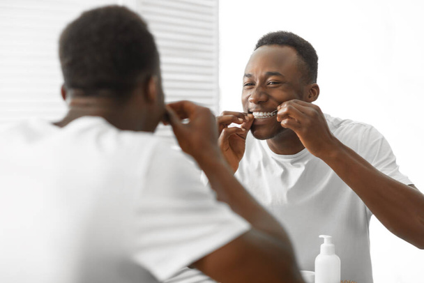 Black Man Cleaning Teeth With Floss In Bathroom At Home - Photo, Image