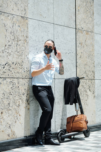 Wütender emotionaler Geschäftsmann steht draußen und telefoniert mit Mitarbeiter - Foto, Bild