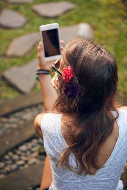 Blanke jonge vrouw met behulp van moderne smartphone in oosterse tuin. - Foto, afbeelding