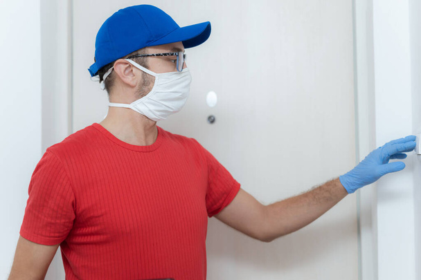 Delivery guy with protective mask holding pizza box at the door. - 写真・画像