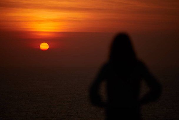 Silhouet van een vrouw met tropische zonsondergang boven de oceaan. - Foto, afbeelding