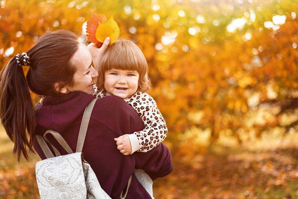 portrait smiling mother and daughter in autumn park, forest, walking in fresh air, happy childhood, motherhood, copy space, unconditional love - Photo, Image