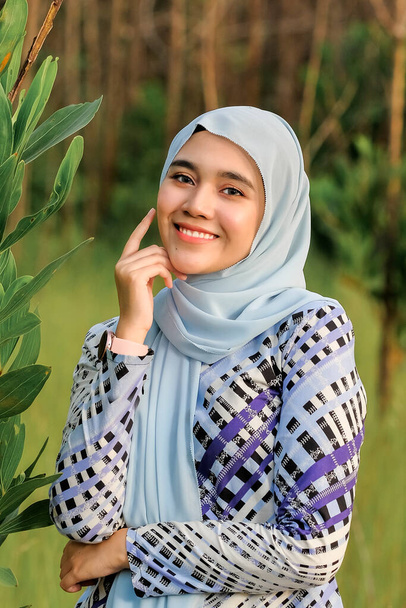Bellissimo modello giovane in stile hijab alla moda in posa in zona verde. Elegante hijab femminile musulmano moda stile di vita concetto di ritrattistica. - Foto, immagini