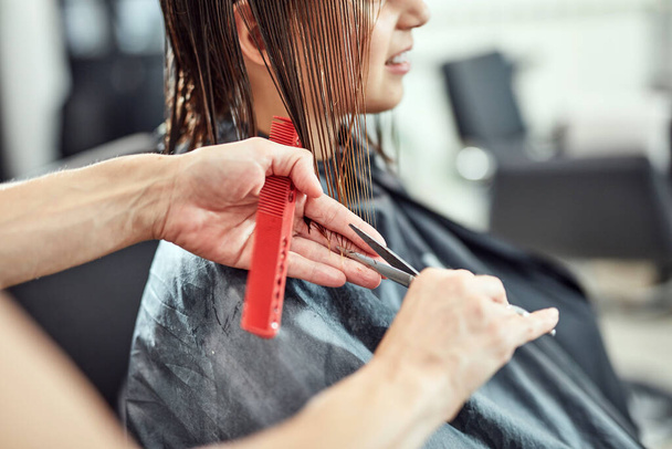 Парикмахер стрижет волосы в салоне. - Фото, изображение