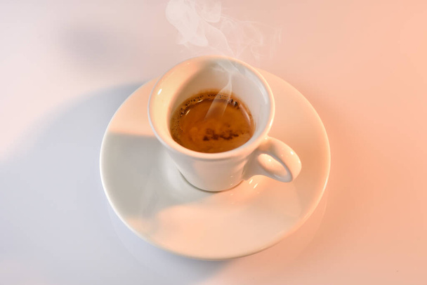 Beyaz bardakta İtalyan espresso, sıcak ışıkla kaynıyor. - Fotoğraf, Görsel