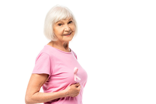 Senior woman looking at camera while touching breast isolated on white, concept of breast cancer  - Foto, imagen