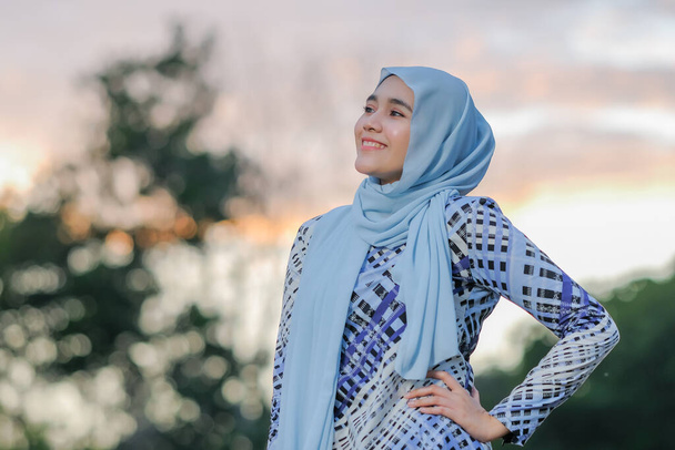 Retrato de una hermosa modelo joven en estilo hijab de moda posando en una hermosa puesta de sol. Estilo musulmán femenino hijab moda estilo de vida retrato concepto. - Foto, imagen