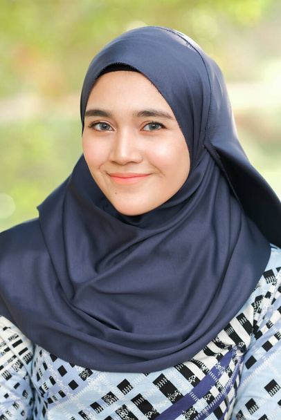 公園でポーズファッショナブルなヒジャーブスタイルの美しい若いモデル。スタイリッシュなイスラム教徒の女性のヒジャーブファッションライフスタイルの肖像コンセプト. - 写真・画像