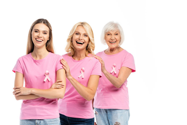 Возбужденные женщины с розовыми лентами осведомлённости о раке груди обнимаются изолированно на белом - Фото, изображение