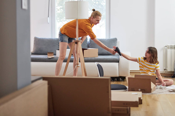 Mother and daughter assembling new furniture - moving in into a new home. - Fotografie, Obrázek