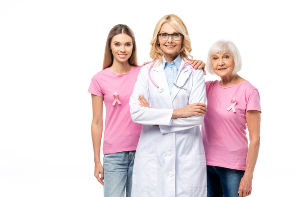 Frauen mit Bändern des Brustkrebsbewusstseins umarmen Arzt isoliert auf weiß - Foto, Bild