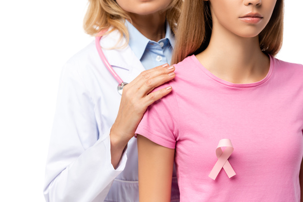 Обрезанный вид доктора, обнимающего молодую женщину с розовой лентой на футболке, изолированной на белом - Фото, изображение