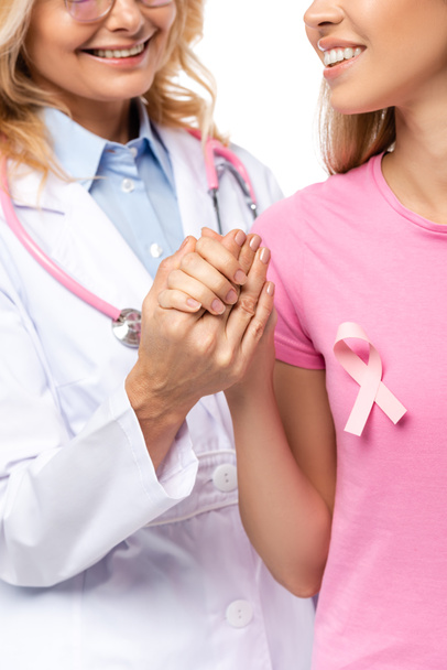 Cropped view of doctor holding hand of young woman with pink ribbon on t-shirt isolated on white - Photo, Image