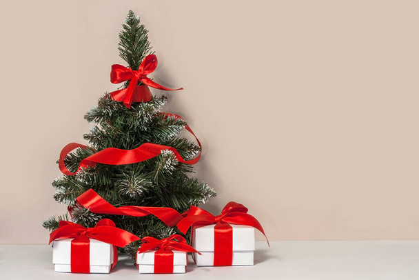 光の壁の近くに飾られたクリスマスツリーと贈り物。クリスマスと新年のお祝いのコンセプト. - 写真・画像
