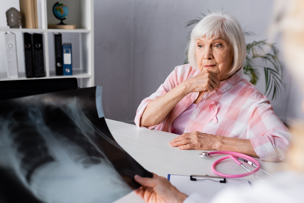 Selective focus of pensive senior woman sitting near doctor with chest x-ray - Photo, Image
