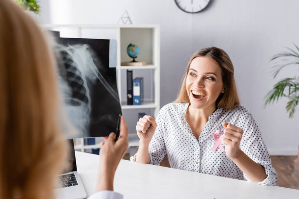 Selective focus of young adult woman with yeah gesture near doctor with x-ray - Fotó, kép