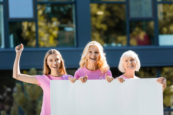 Mulheres excitadas segurando placa vazia com edifício no fundo - Foto, Imagem