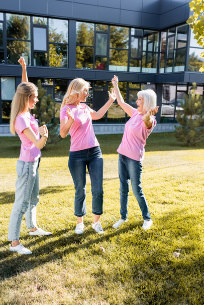 Trois femmes excitées portant des t-shirts roses avec des rubans de sensibilisation au cancer du sein - Photo, image