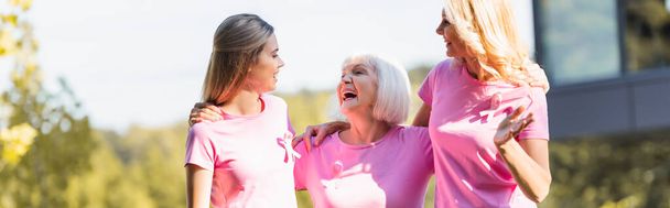 Panoramaaufnahme von drei Frauen, die sich umarmen und lachen, Konzept von Brustkrebs - Foto, Bild