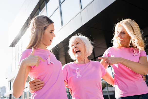 Women laughing and pointing with fingers at sign of breast cancer awareness - Photo, Image