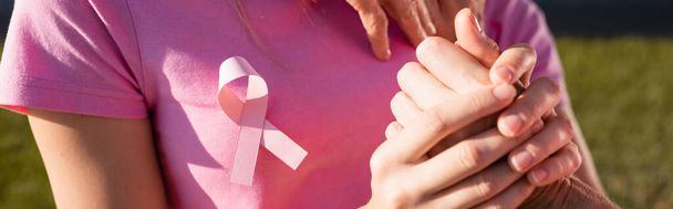 Panoramic shot of woman with sign of breast cancer awareness holding hand  - Foto, afbeelding