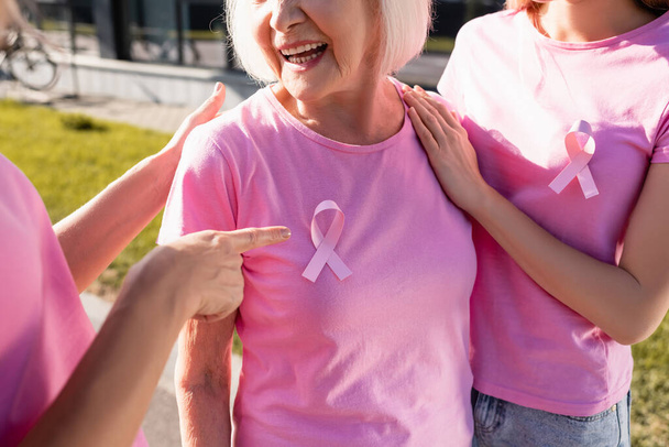 Ausgeschnittene Ansicht einer Frau, die mit dem Finger auf rosa Band im Freien zeigt - Foto, Bild