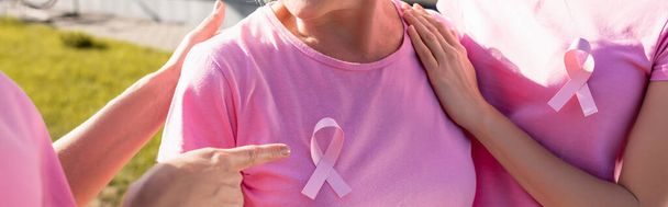Panoramic shot of woman pointing with finger at pink ribbon on woman's t-shirt - Foto, afbeelding