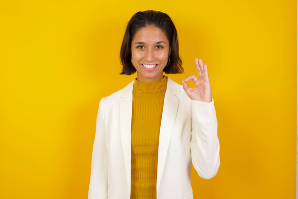 Glad attractive woman shows ok sign with hand as expresses approval, has cheerful expression, being optimistic - Photo, Image