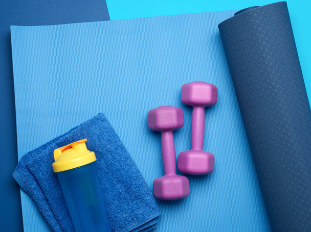 pair of dumbbells, sports gloves and blue sports mat, top view - Photo, Image
