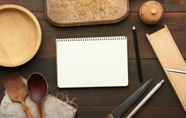 caderno aberto com folhas brancas em branco e utensílios de cozinha em mesa de madeira marrom, vista superior - Foto, Imagem