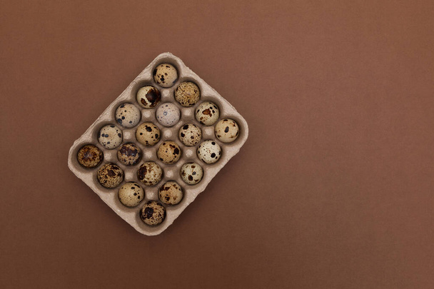 Quail eggs in package on brown background with copy space. Top view. - Foto, imagen
