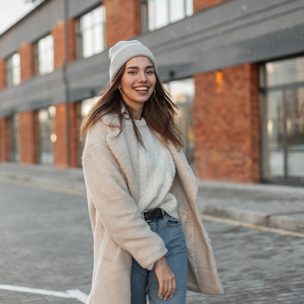 Pretty model of a happy young woman in fashionable casual youth spring outerwear enjoys a walk on the street in the city. Attractive happy girl with a positive smile in trendy clothes. Spring fashion. - Photo, Image