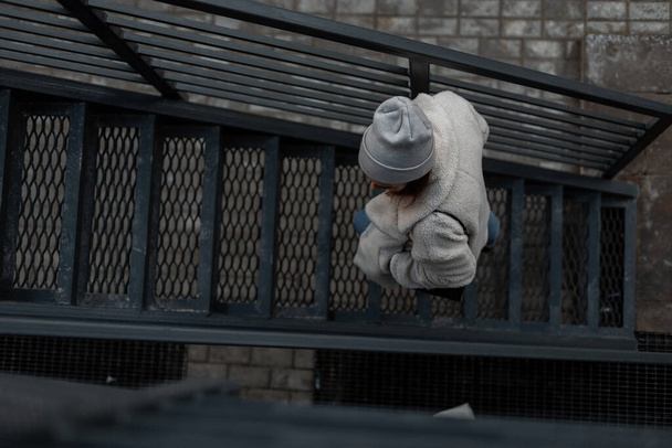 mladá moderní žena v módních teplých pletených šatech na kovovém schodišti. Stylová dívka jde po železných schodech. Jaro. Mládež. Horní pohled - Fotografie, Obrázek