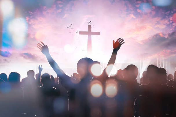 křesťanské skupiny lidí zvednout ruce nahoru uctívání Boha Ježíše Krista společně na kříži přes zamračené nebe pozadí - Fotografie, Obrázek