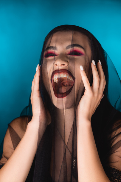 evil bride with black makeup and veil laughing on blue - 写真・画像