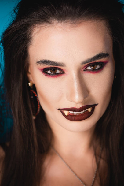 vampire with black makeup and white scary teeth looking at camera  - Zdjęcie, obraz