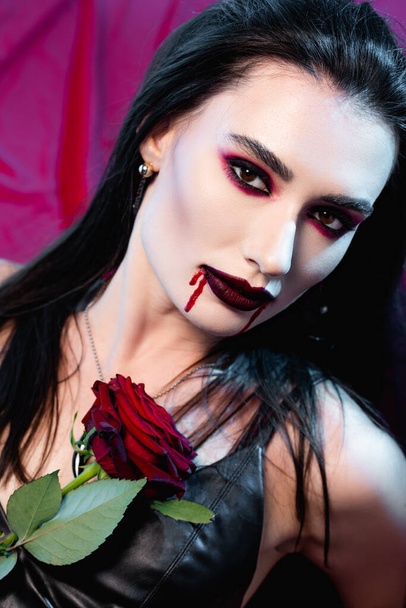 mujer pálida con sangre en la cara y se levantó mirando a la cámara en rojo - Foto, Imagen