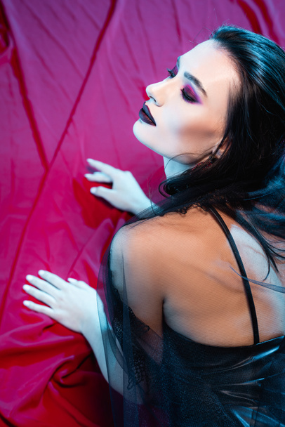 pale and young woman with black makeup on red - Fotografie, Obrázek