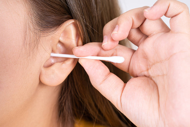 donna pulirsi l'orecchio con un batuffolo di cotone. Una donna ha subito un'infezione dopo aver usato i bastoni in modo errato. - Foto, immagini