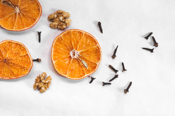 Naranjas secas con diseño de frutos secos y clavos. Fondo de tema otoño / invierno desde la vista superior. - Foto, Imagen