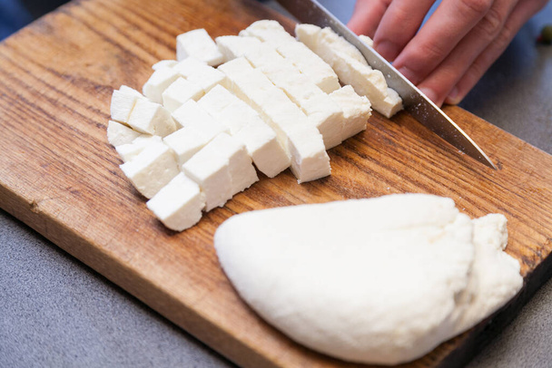Cutting paneer into pieces on wooden board - Photo, Image