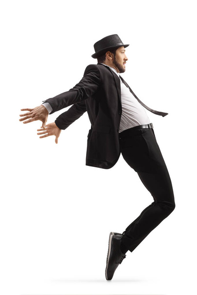 Full length profile shot of a man in a suit and hat dancing on tiptoes isolated on white background - Photo, Image