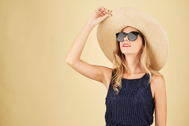 Retrato de jovem elegante na moda em chapéu de palha e óculos de sol olhando para cima - Foto, Imagem