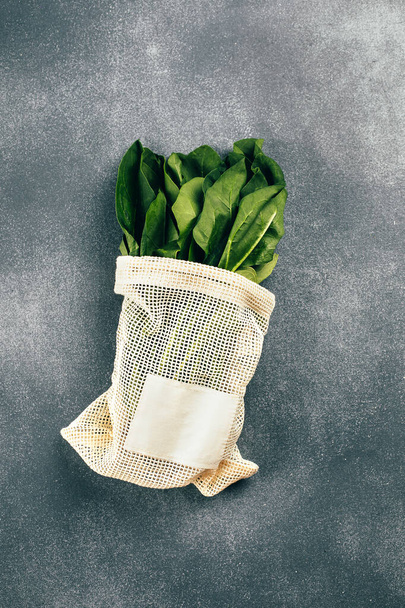 Spinach in eco cotton bags on table. Zero waste shopping concept. Flat lay, top view. - Photo, Image