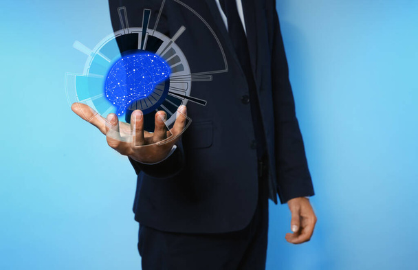 Businessman holding digital image of brain in hand on blue background, closeup Machine learning concept  - Valokuva, kuva
