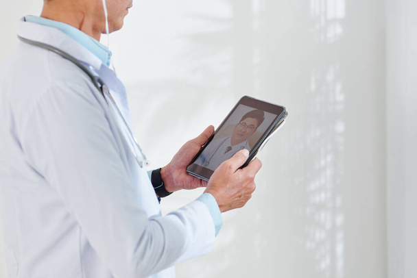 Przycięty obraz lekarza wideo dzwoniącego do kolegi przez tablet - Zdjęcie, obraz