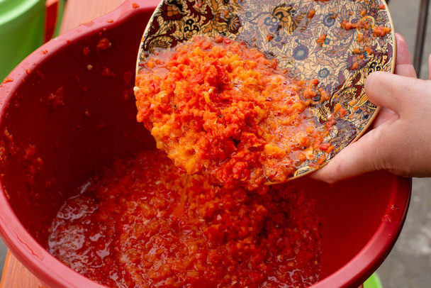 Ajvar frais fait de tomates et de paprika sur la table en bois rustique. Ajvar avec main de femme. - Photo, image