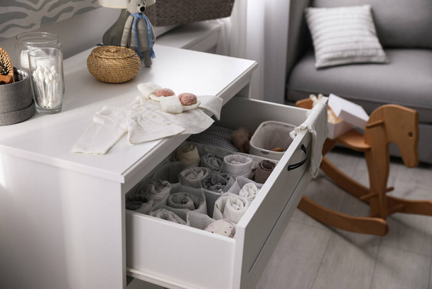 Modern open chest of drawers with baby clothes and accessories in room - Fotó, kép